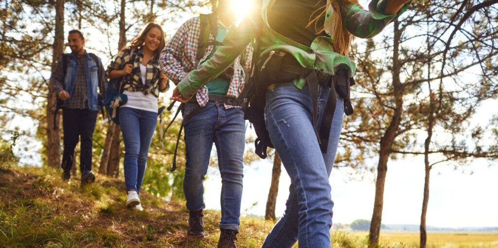 Young people with backpacks walking in the forest